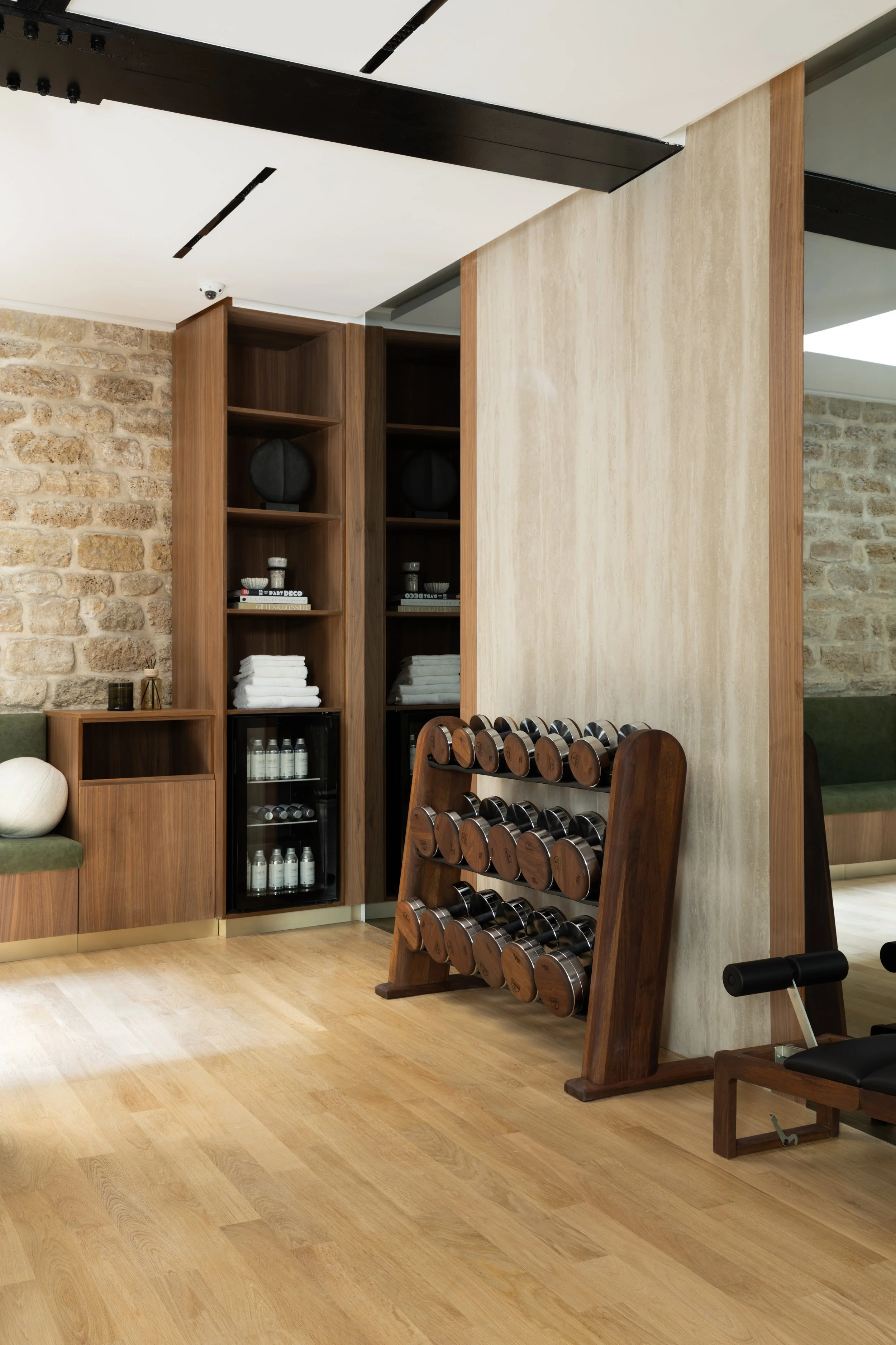 Salle de sport privée haut de gamme à Paris, avec mobilier sur mesure en bois et pierre naturelle – Intérieurs Chomet.