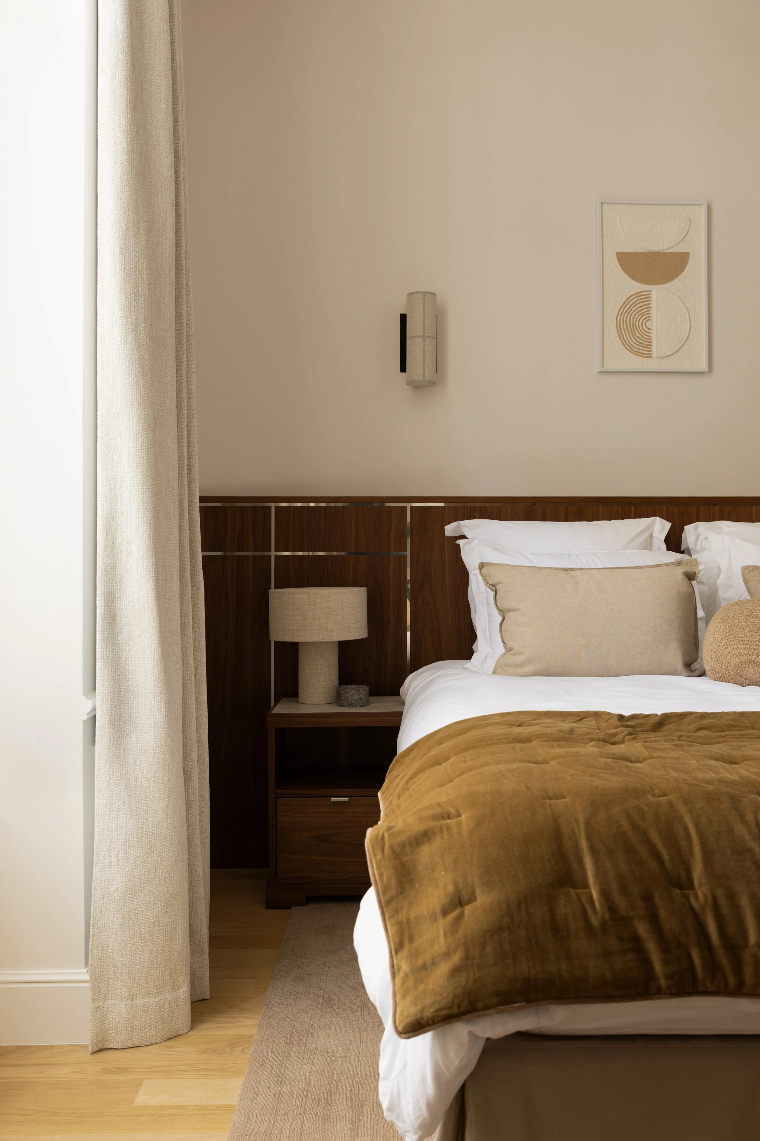 Décoration d'une chambre élégante à Paris avec tête de lit en noyer sur mesure, linge de lit raffiné et couvre-lit ocre – Intérieurs Chomet.
