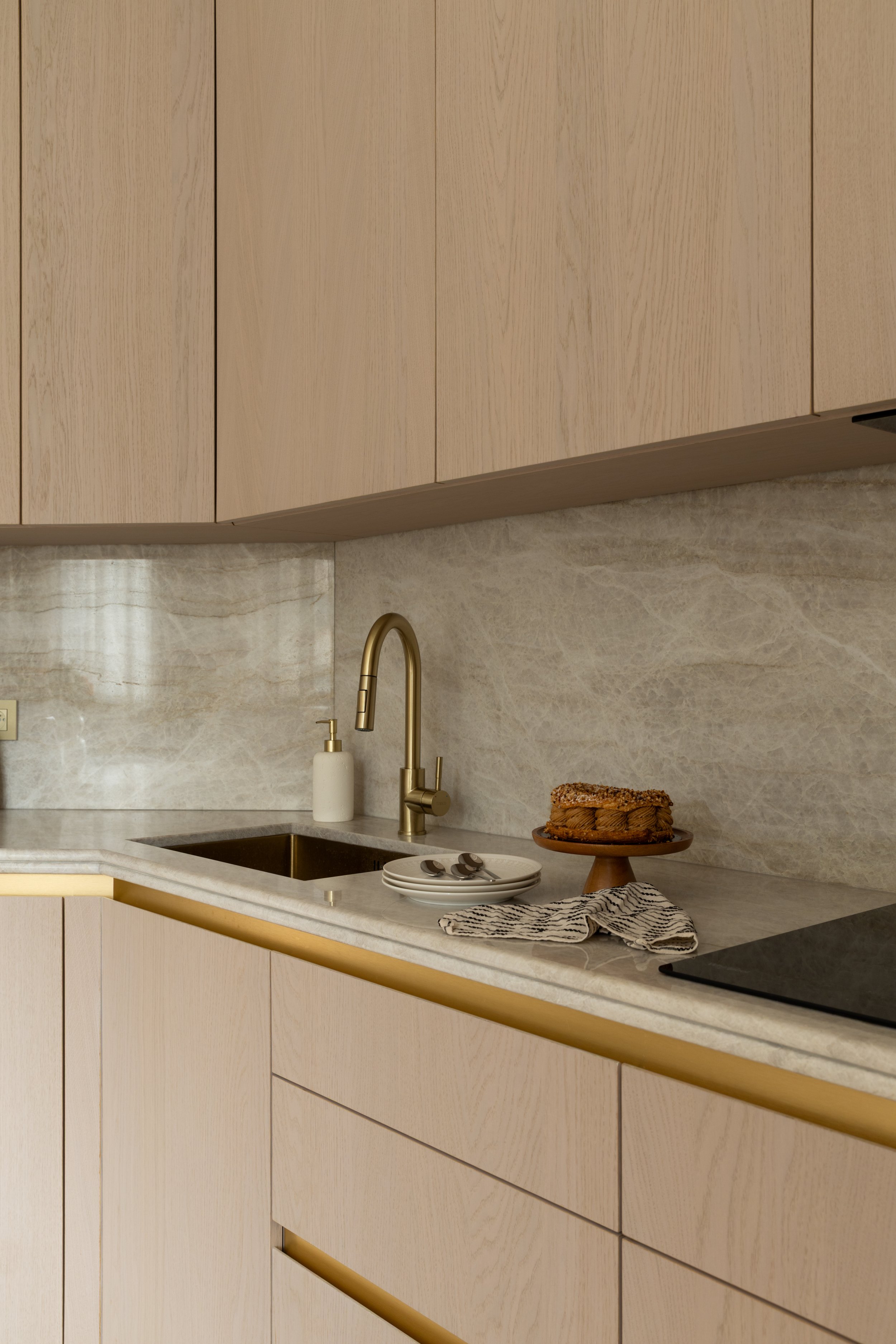 Plan de travail en pierre naturelle avec évier intégré et robinetterie dorée.