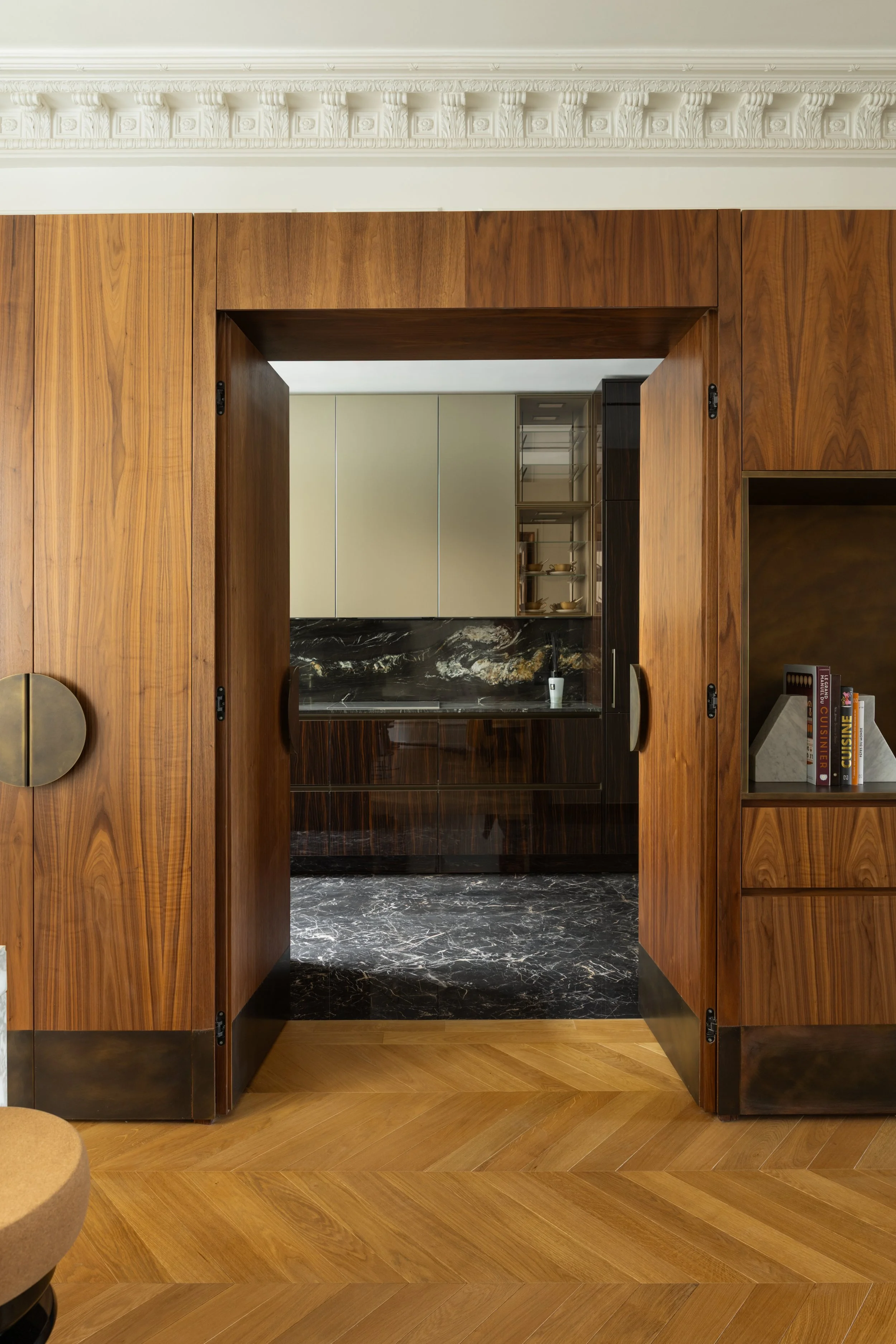 Cuisine sur mesure en bois foncé et pierre naturelle, décoration intérieure haut de gamme dans un appartement parisien.