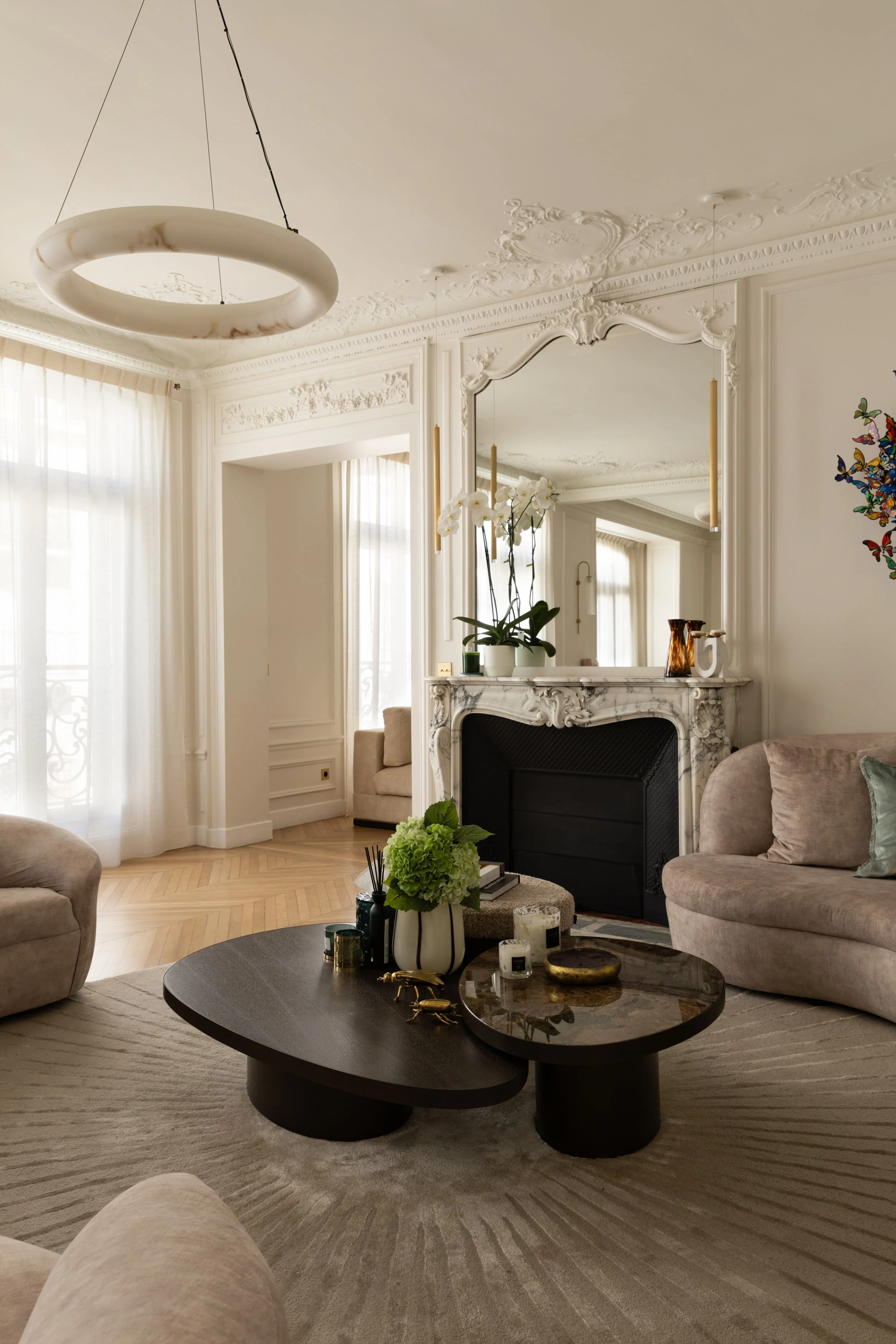 Salon haussmannien du projet Malesherbes à Paris, avec cheminée en marbre, moulures ouvragées, canapés arrondis et tables basses sculpturales — Intérieurs Chomet.