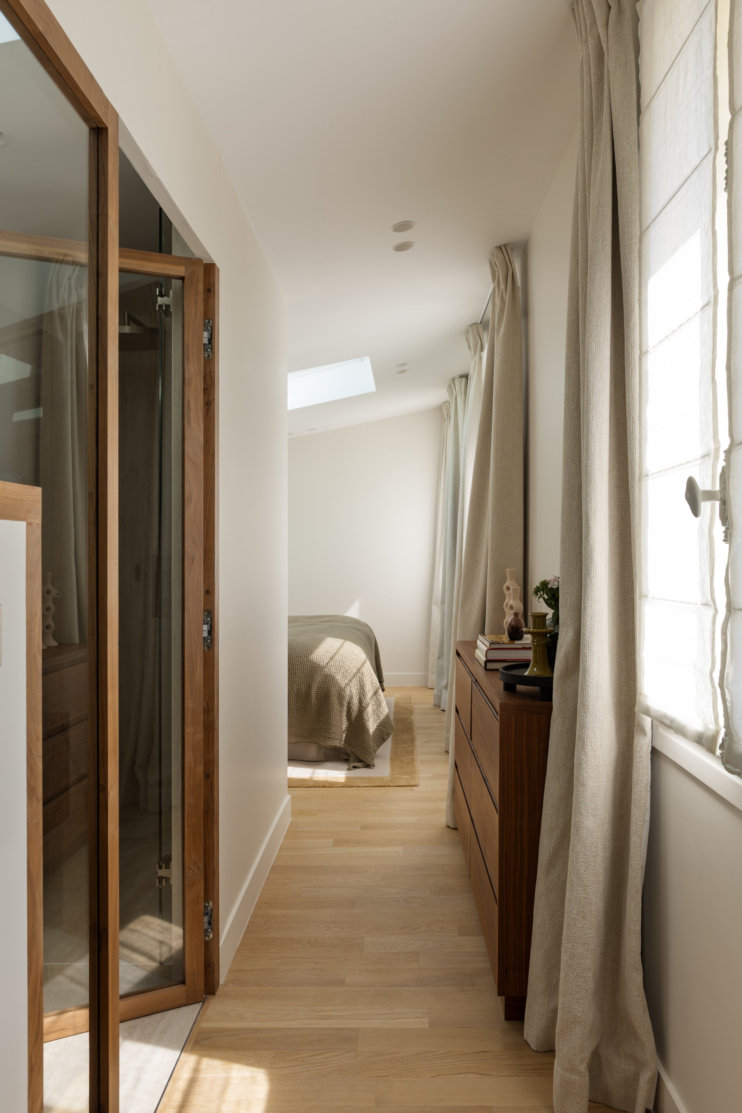 Aménagement d'une suite parentale à Paris avec couloir lumineux, parquet en chêne clair, menuiseries sur mesure et salle de bains attenante – Intérieurs Chomet.