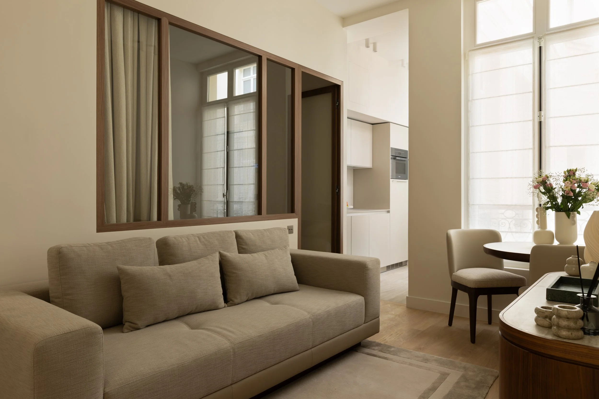 Aménagement d'un petit appartement à Paris avec verrière intérieure, canapé contemporain, cuisine ouverte et rangements intégrés – Intérieurs Chomet.