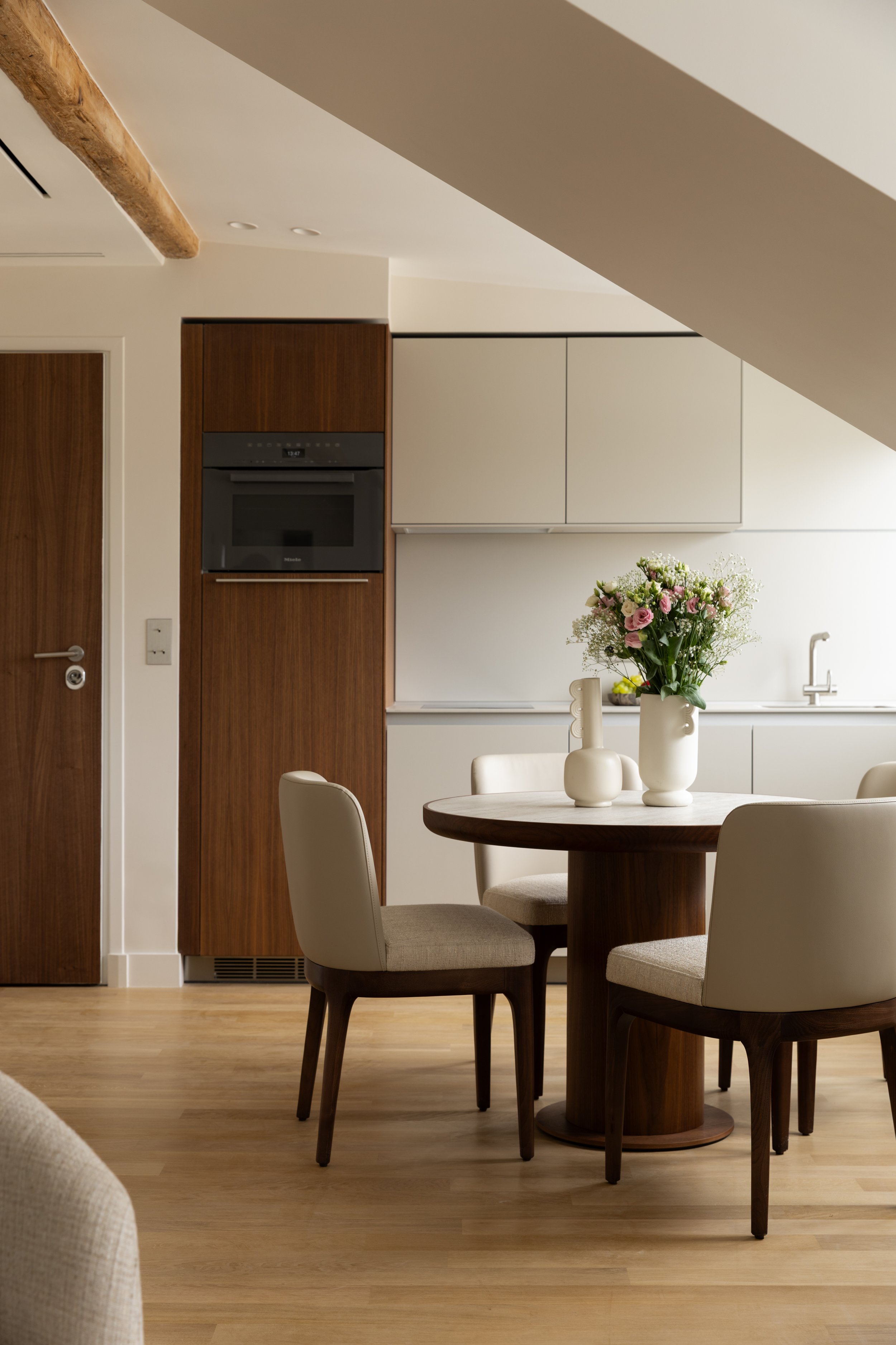 Cuisine ouverte sous les combles à Paris avec mobilier contemporain, façades épurées et table en bois sur mesure – Intérieurs Chomet.