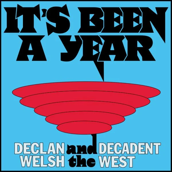 Book cover with the title "It's Been a Year" in large black letters at the top, and "Declan and Decadent Welsh of the West" at the bottom. The center features a red, layered, UFO-like shape on a blue background.