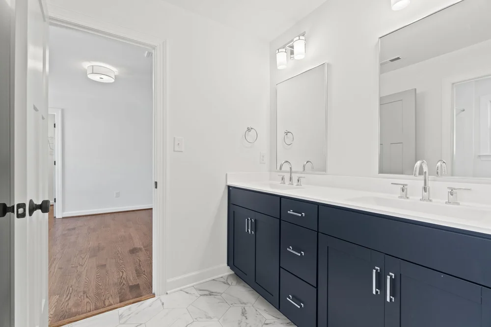 Bathroom with double vanity, dark blue cabinets, and modern lighting.