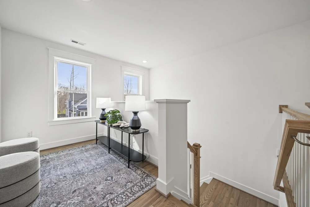 Bright seating area by windows with a rug and small console table.