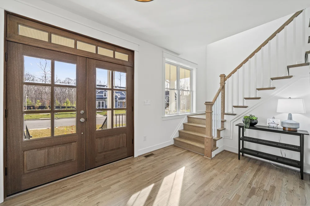 "Entryway with a wooden front door, side windows, and staircase
