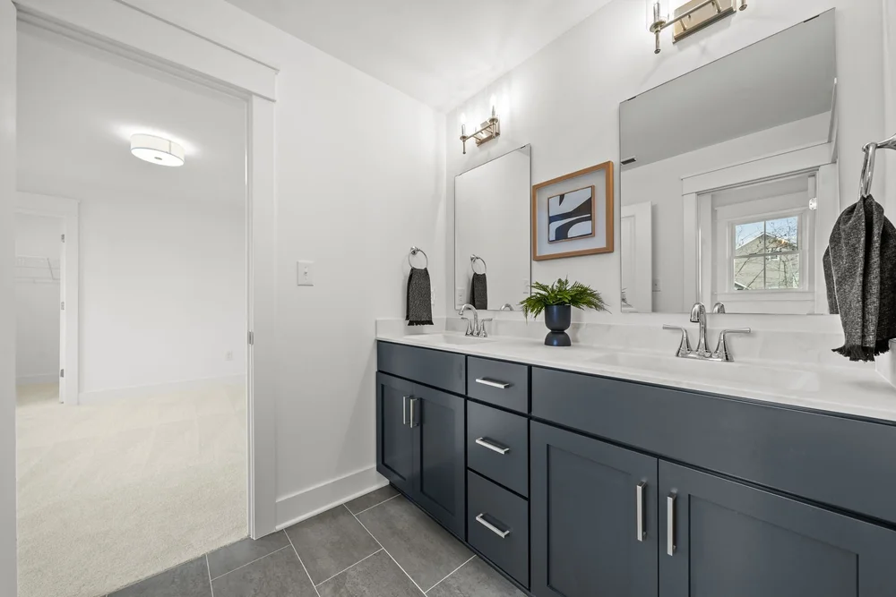 Bathroom with double sink vanity, dark cabinets, and large mirror.
