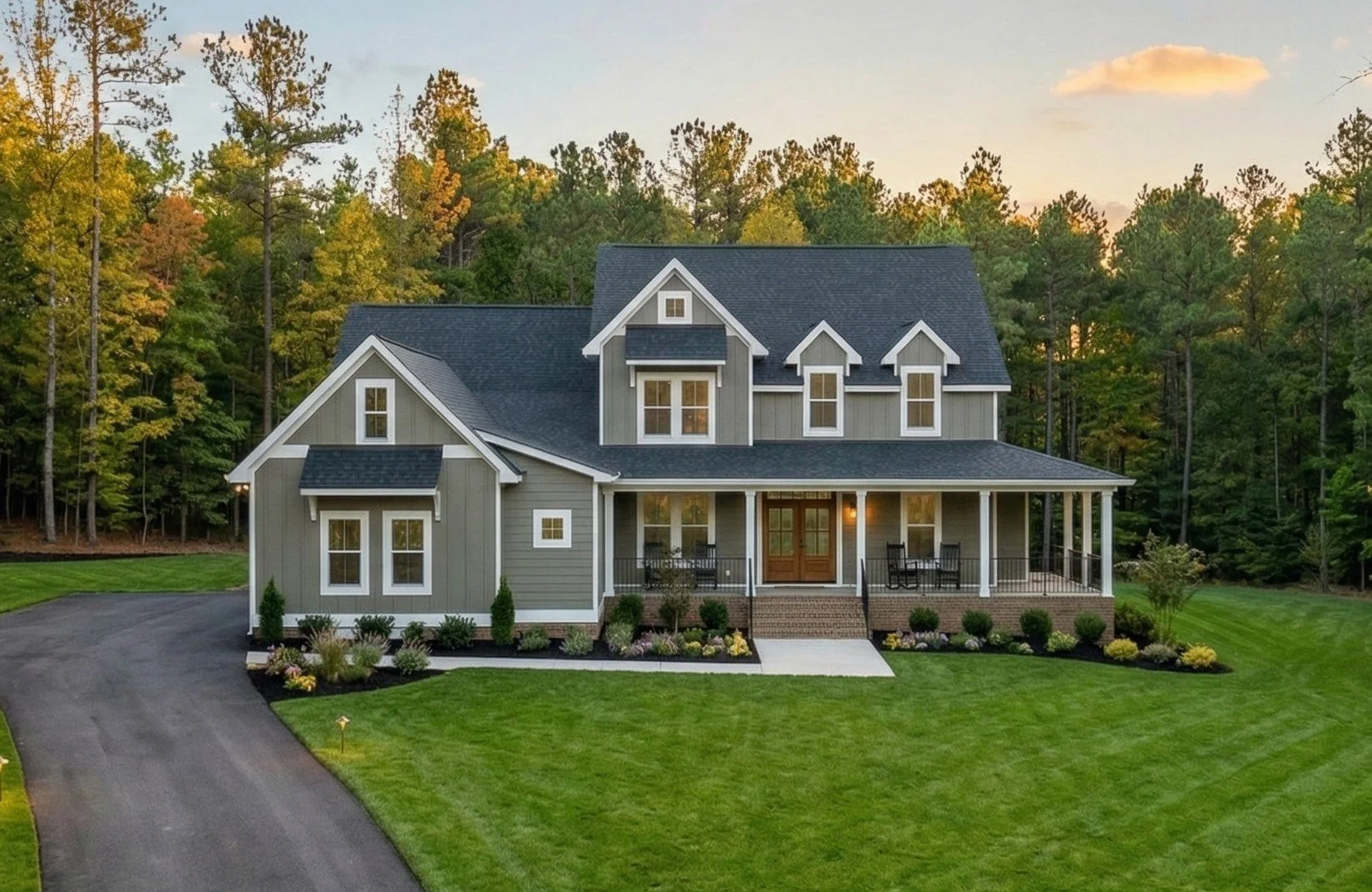 A two-story house with a large front porch, gray siding, black roof, and white trim, surrounded by a green lawn and trees.