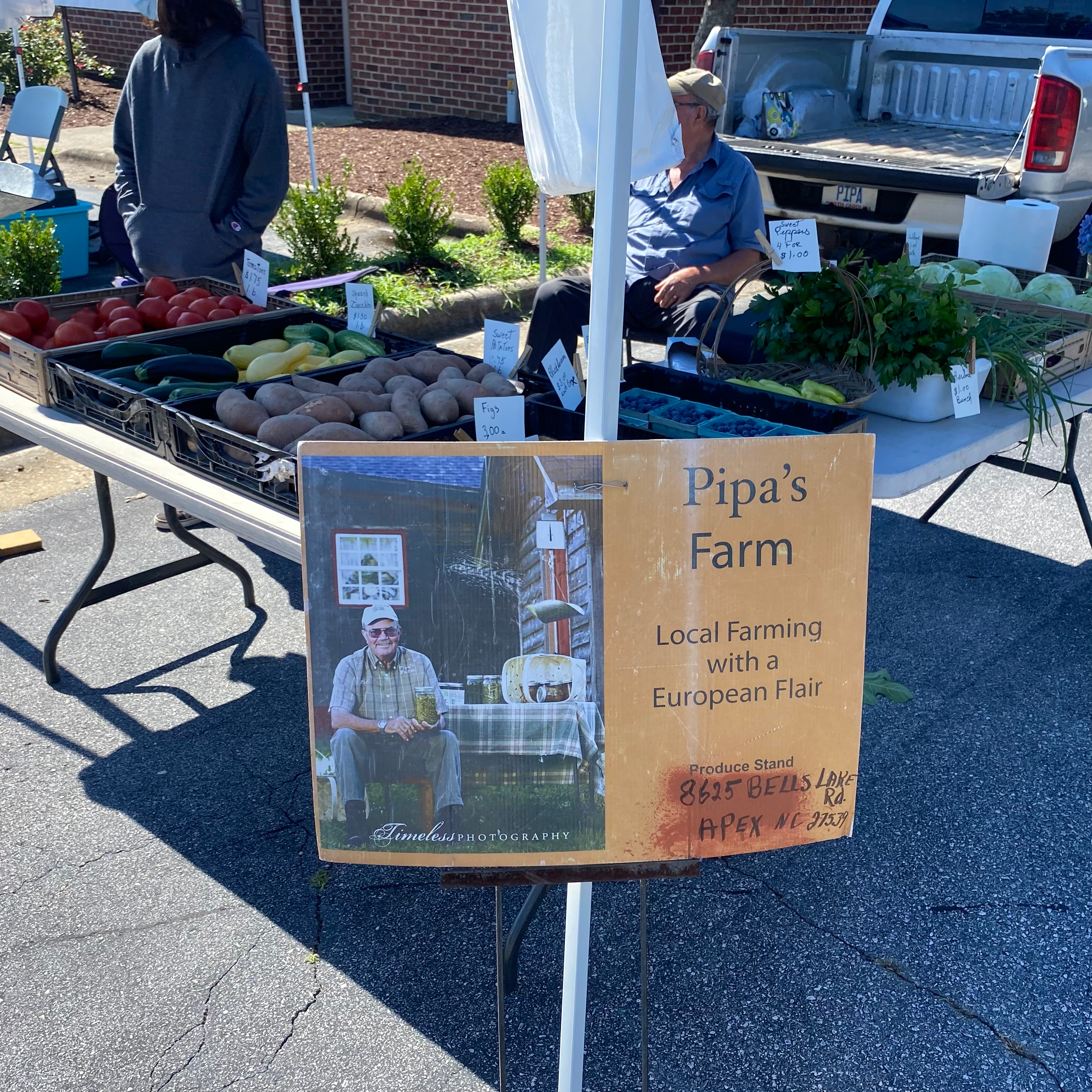 Farmers market stall with vegetables and Pipa's Farm sign, promoting local farming in Apex, NC.