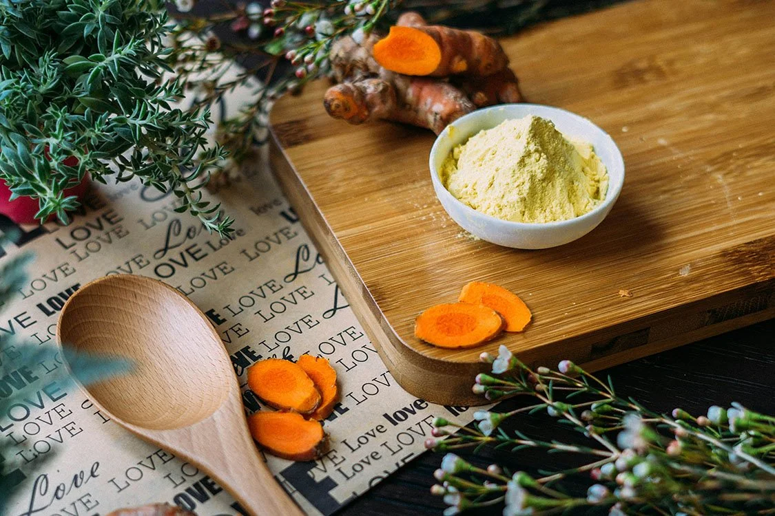 Ayurvedic herbs and spices including turmeric root and powder prepared on a wooden surface to support seasonal wellness