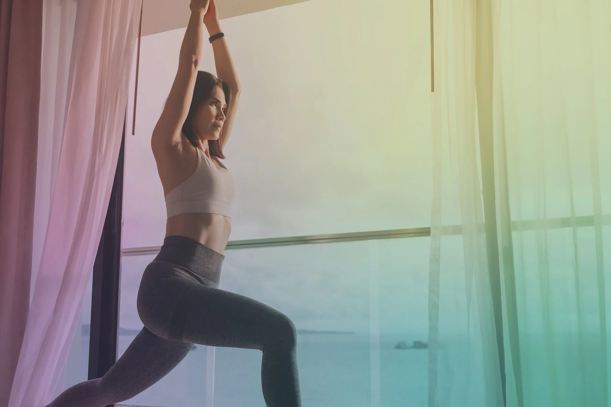 Woman practicing yoga on a hotel balcony overlooking the ocean while traveling
