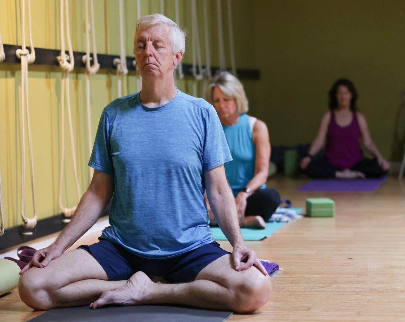 Students seated in meditation with hands in mudra during a yoga class at Prana Yoga Center.
