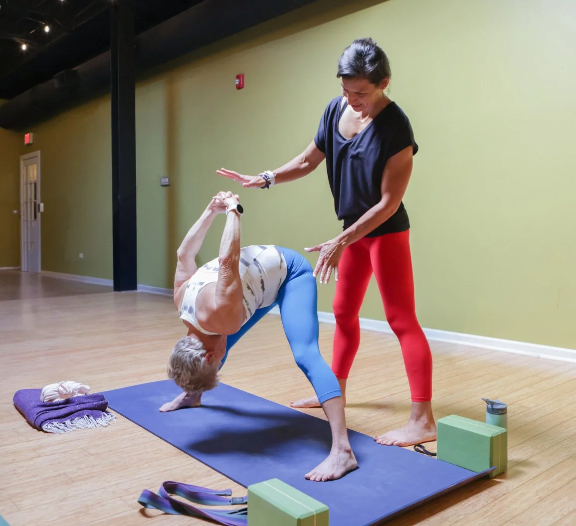 Yoga teacher assisting a student during a private yoga session at Prana Yoga Center in Geneva, Il