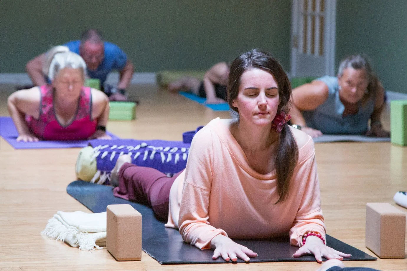 Woman resting in a supported yoga pose during a gentle practice at Prana Yoga Center