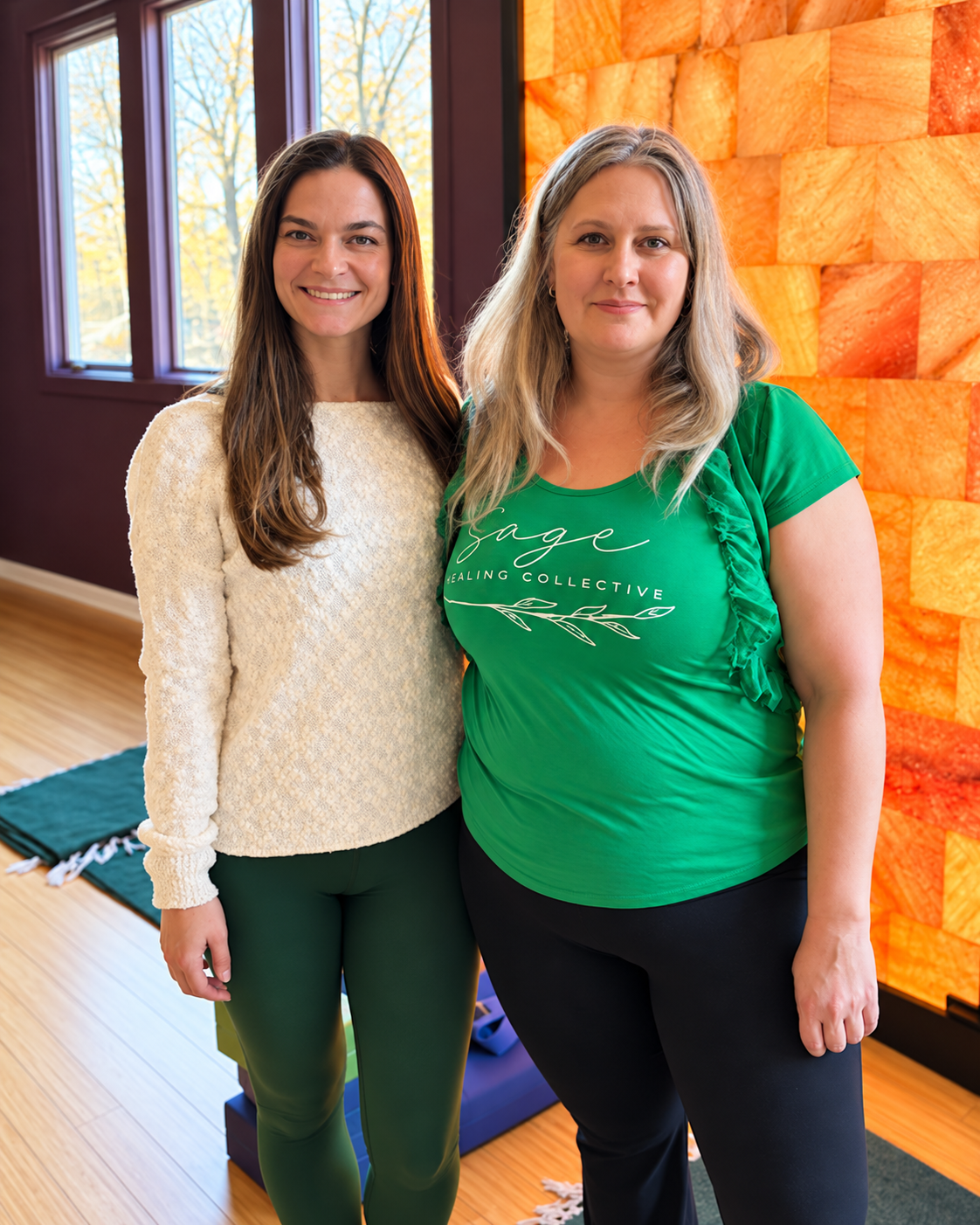 Jessica Taddeo and Amy Yehoshua standing beside the illuminated salt wall at Prana Yoga Center.
