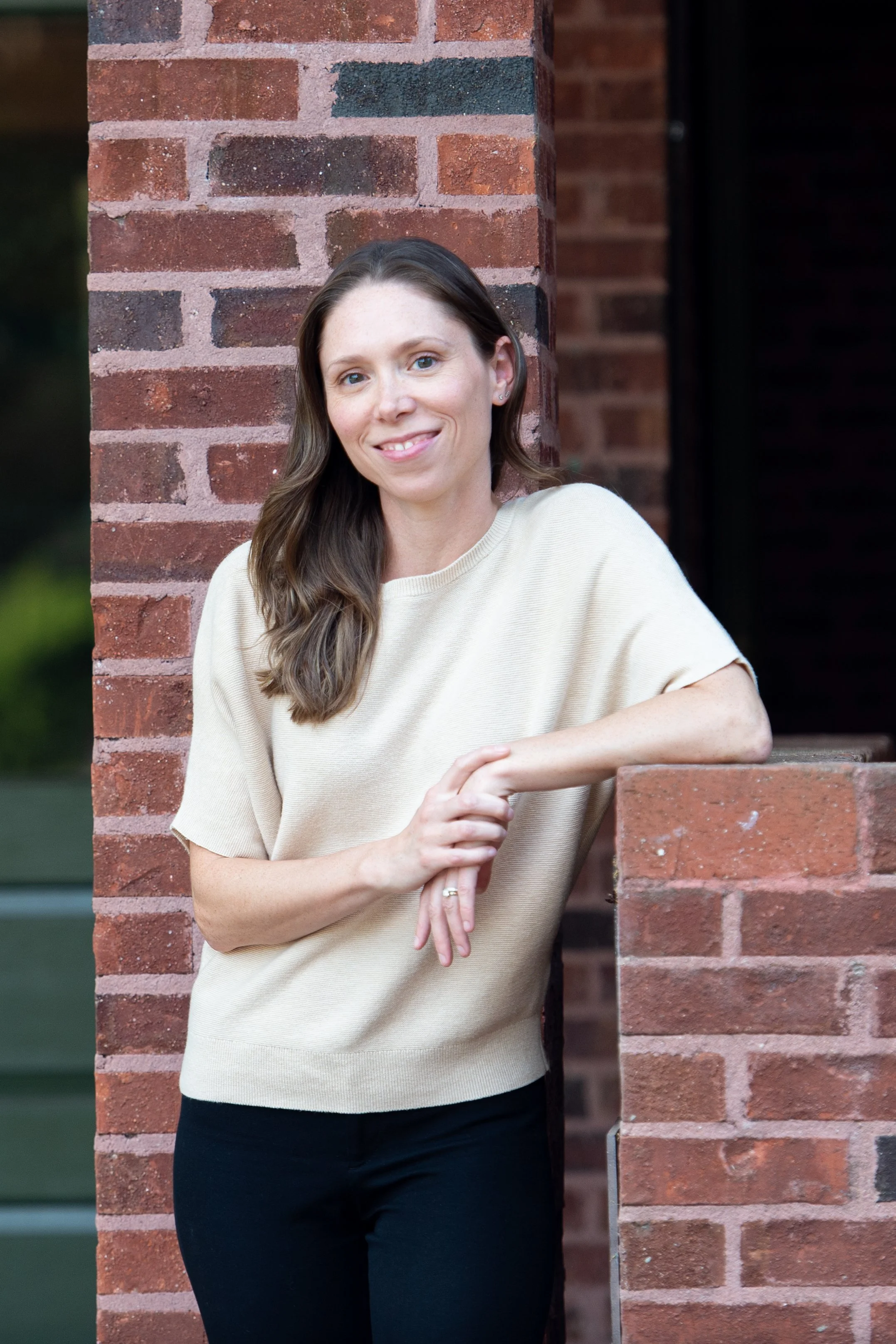 Dr. Jordan Wade standing outside of her Raleigh office, smiling at the camera, wearing a beige short-sleeve sweater and black pants.