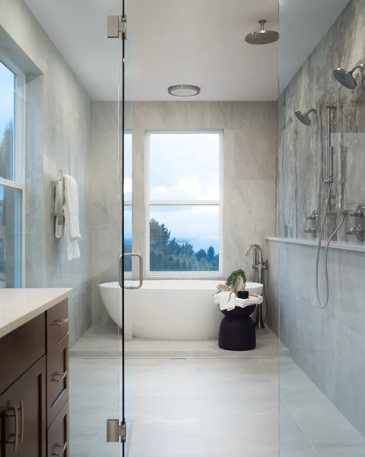 Walk-in glass shower with large-format stone-look tile and freestanding tub