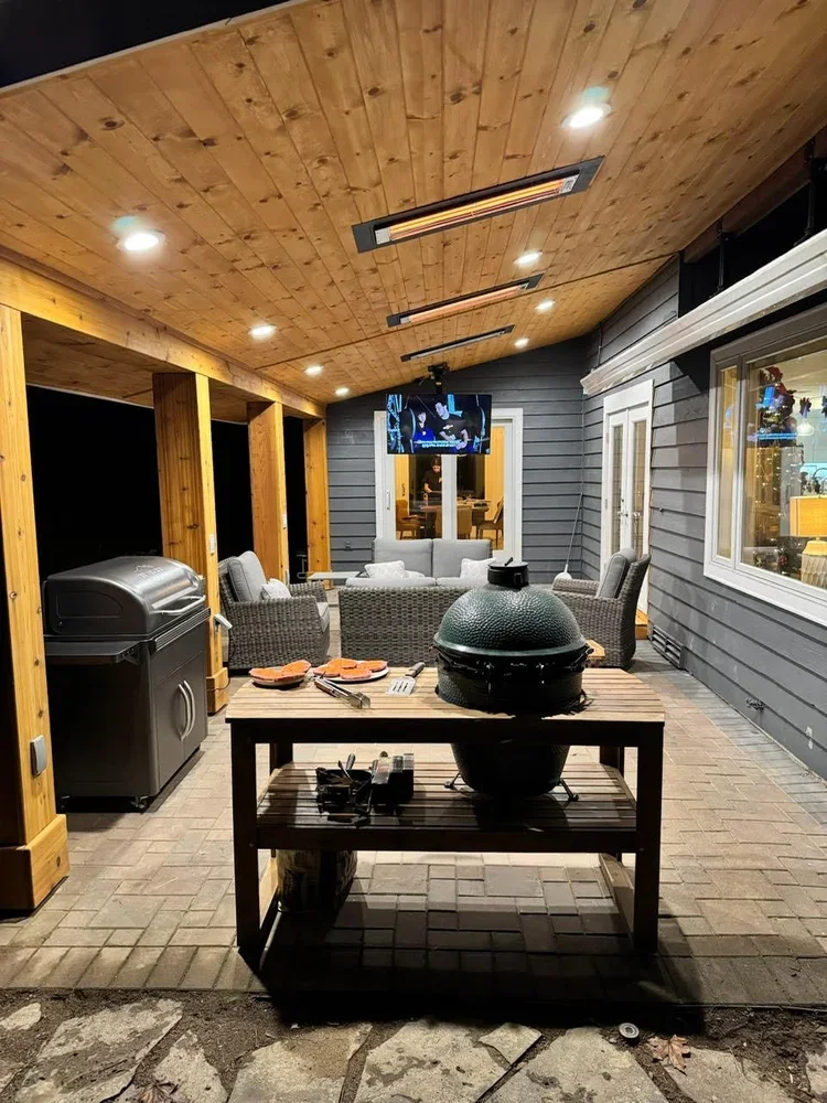 Covered outdoor living area with wood plank ceiling, heaters and grill station