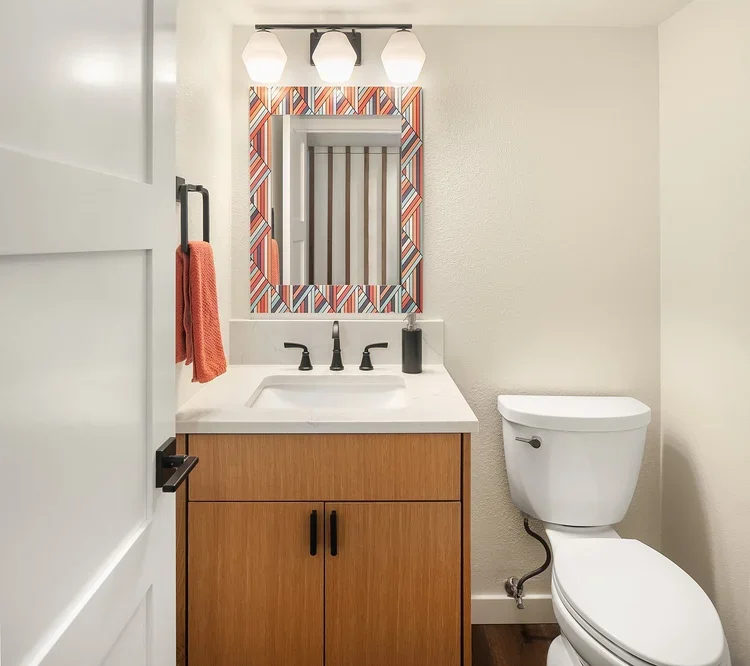 Bathroom with wood vanity, patterned accent wall and black fixtures