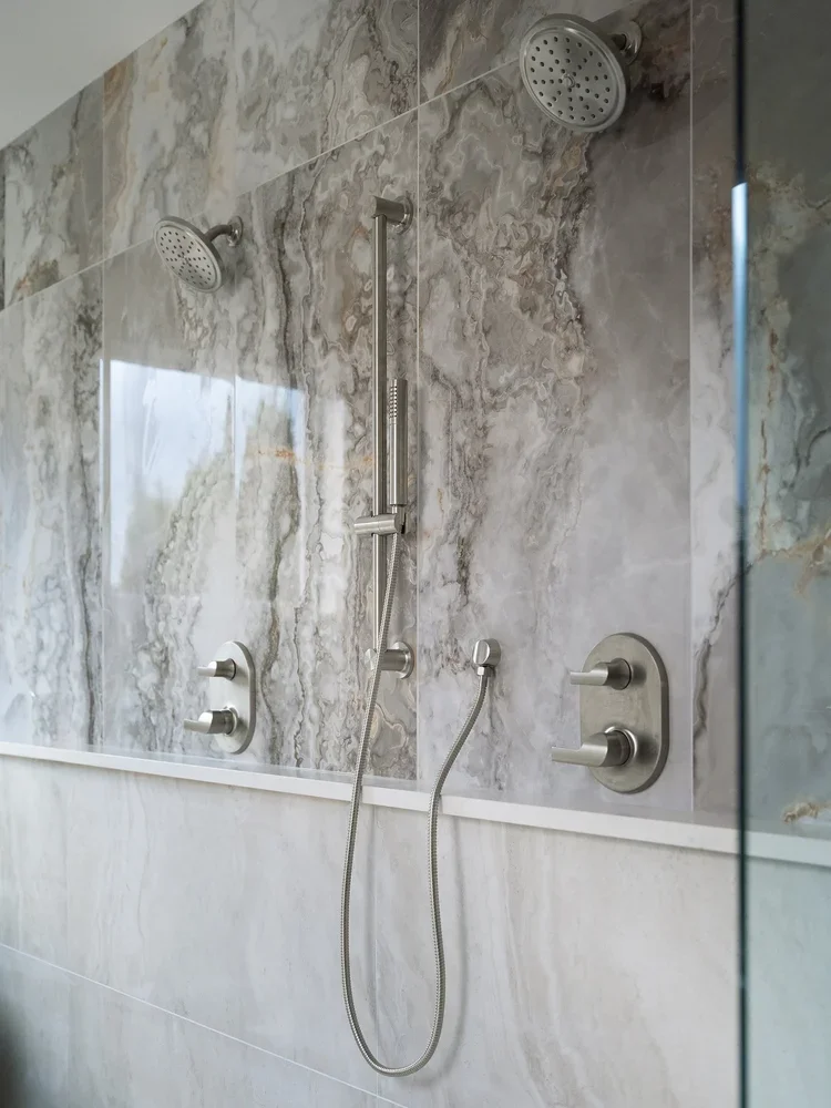 Walk-in shower with marble-look wall panel and brushed nickel fixtures