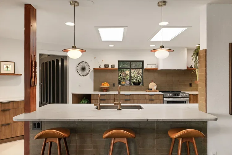 Open kitchen with large quartz island, bar stools and pendant lights