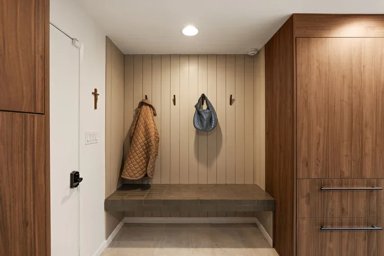 Mudroom with built-in bench, wall hooks and wood storage cabinets