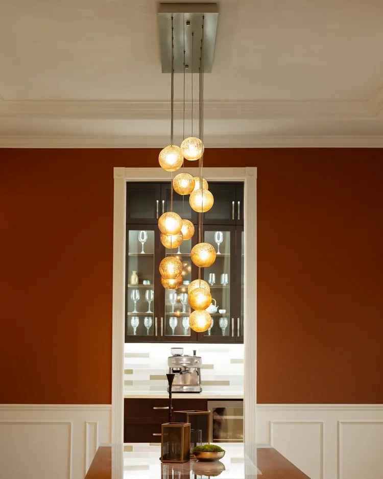 Dining room with cluster pendant light, wainscoting and deep red walls