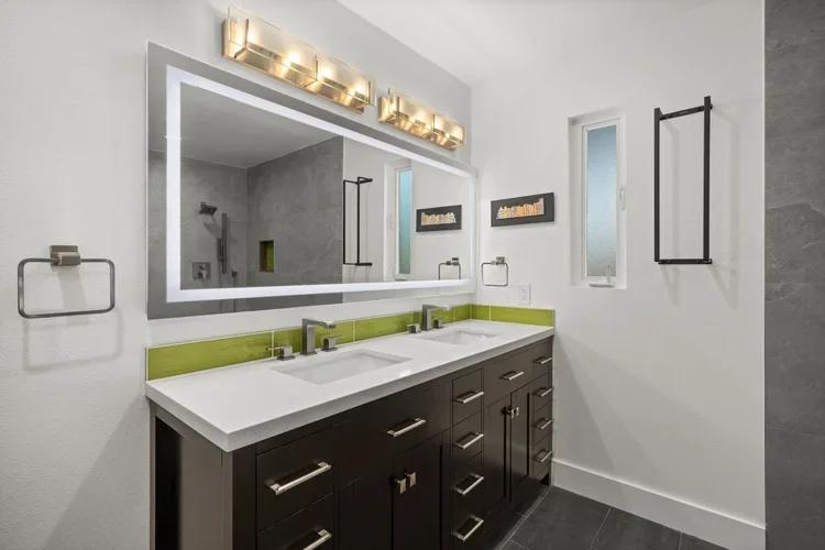 Double vanity with lighted mirror and green accent tile