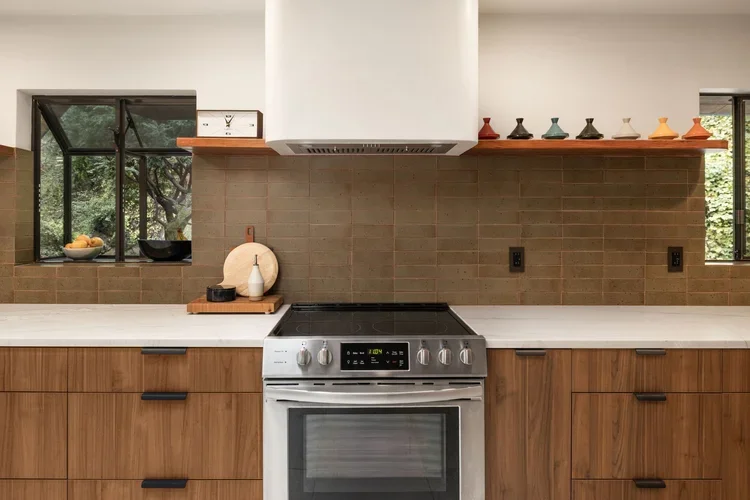 Stainless range with tile backsplash, open wood shelves and white range hood