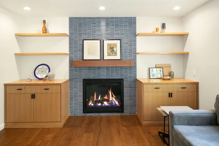 Blue tile fireplace surround with custom wood built-ins and floating shelves