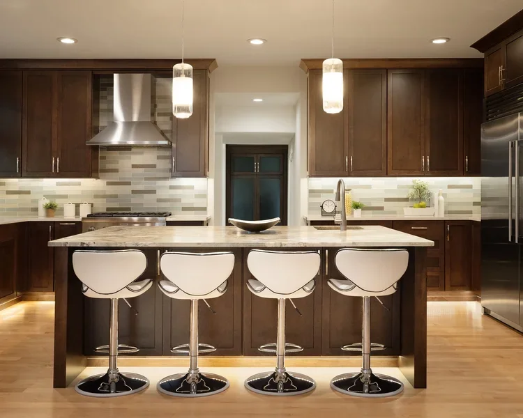 Dark wood kitchen island with white bar stools and pendant lights