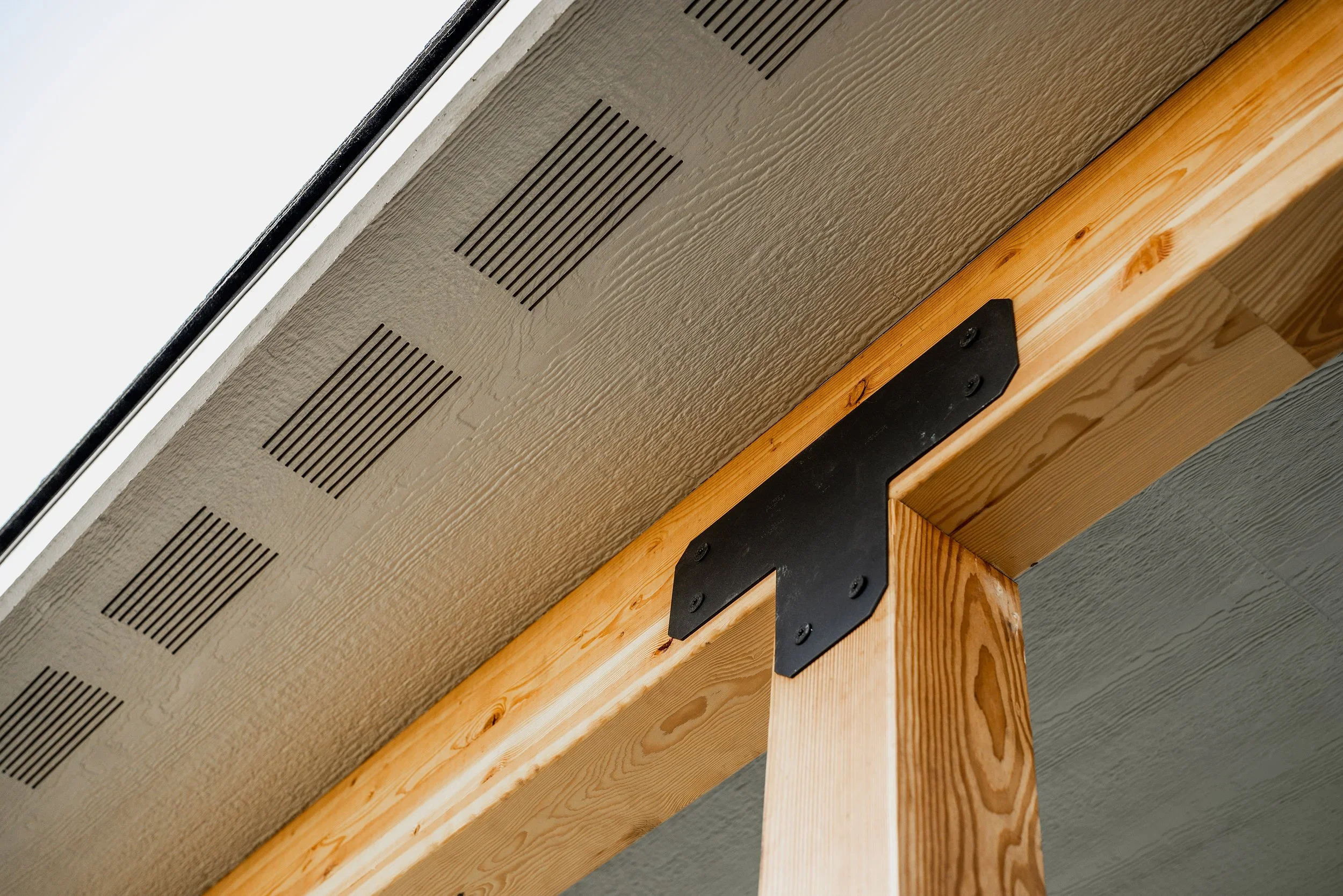 Cedar beam with black steel bracket and new siding with soffit vents