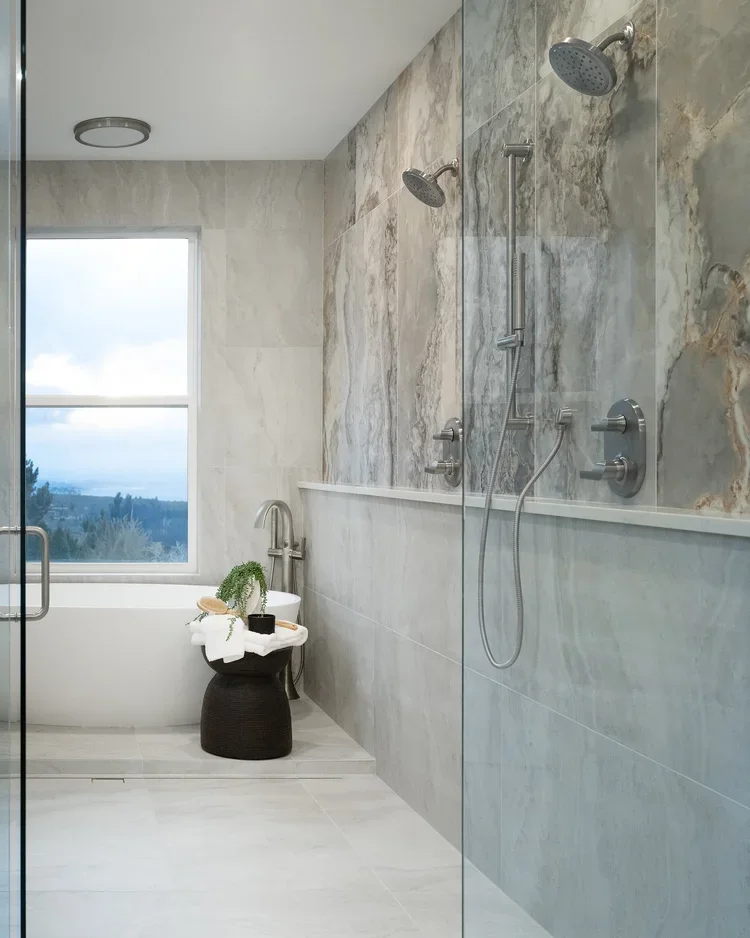 Curbless walk-in shower with marble-look tile wall beside a window