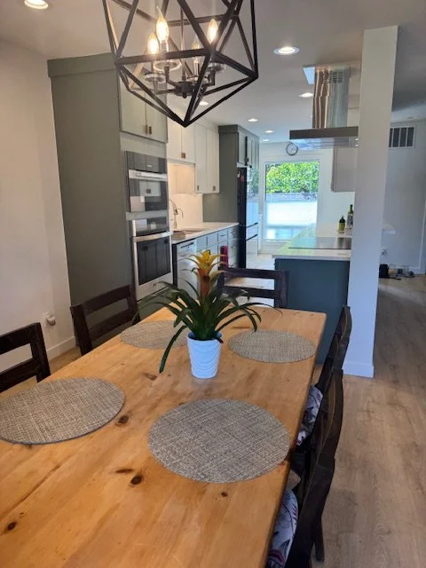 Dining area open to the kitchen with wood table and geometric chandelier