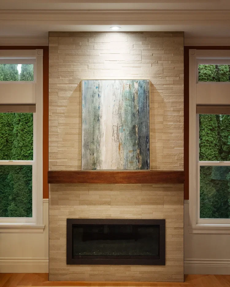 Tile fireplace wall with wood mantel between two windows