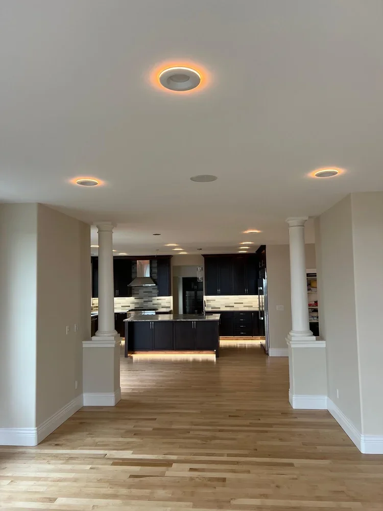 Hallway opening into the kitchen with hardwood floors and recessed lighting