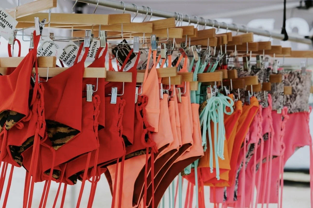 Colorful bikinis hanging on a rack at an outdoor market.