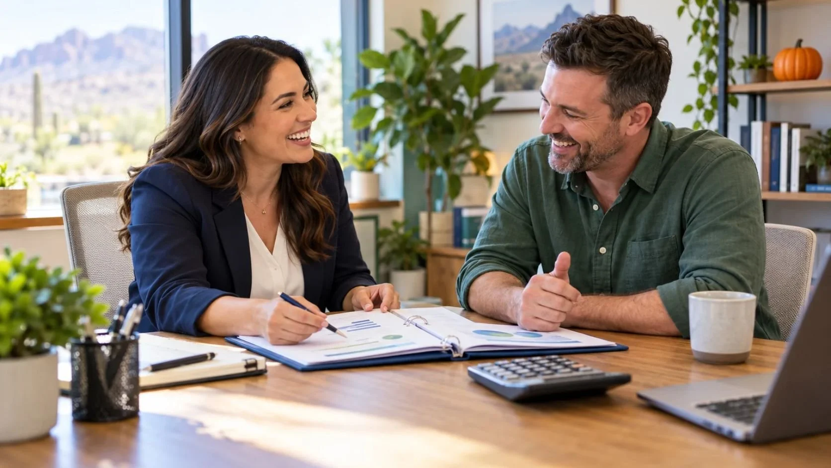 Accountant and business owner smiling over an open binder, with a small pumpkin on an office shelf.