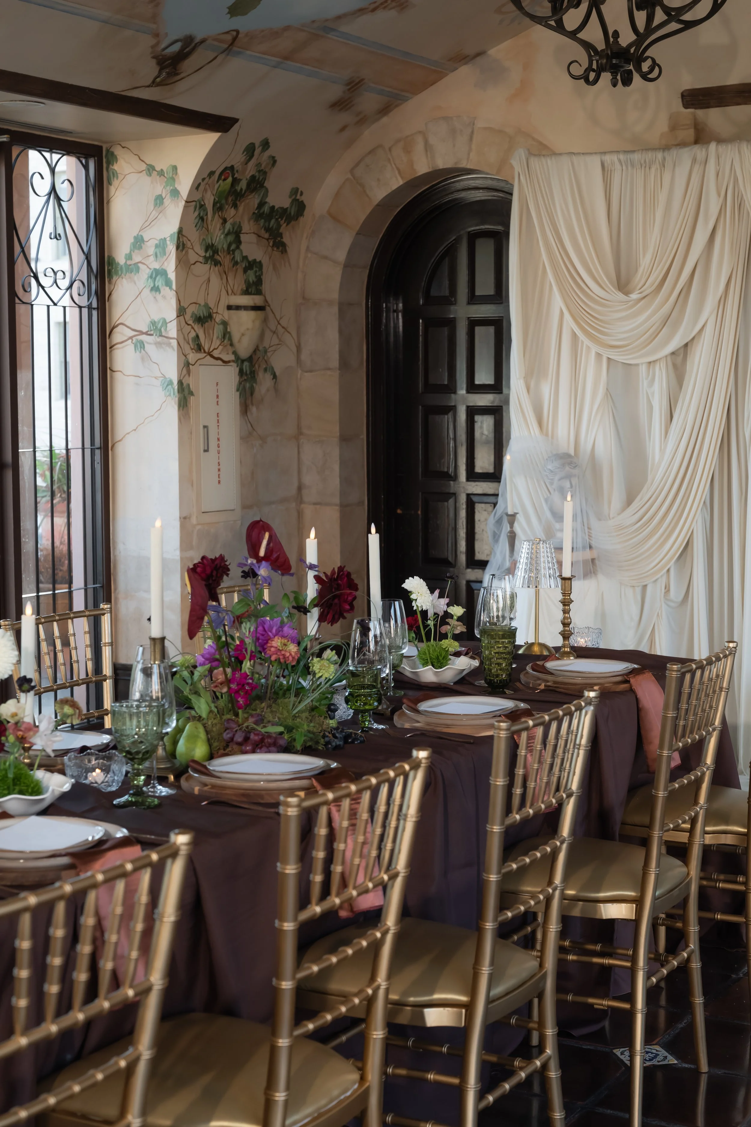 Elegant wedding reception table with gold chairs, flowers and candles.