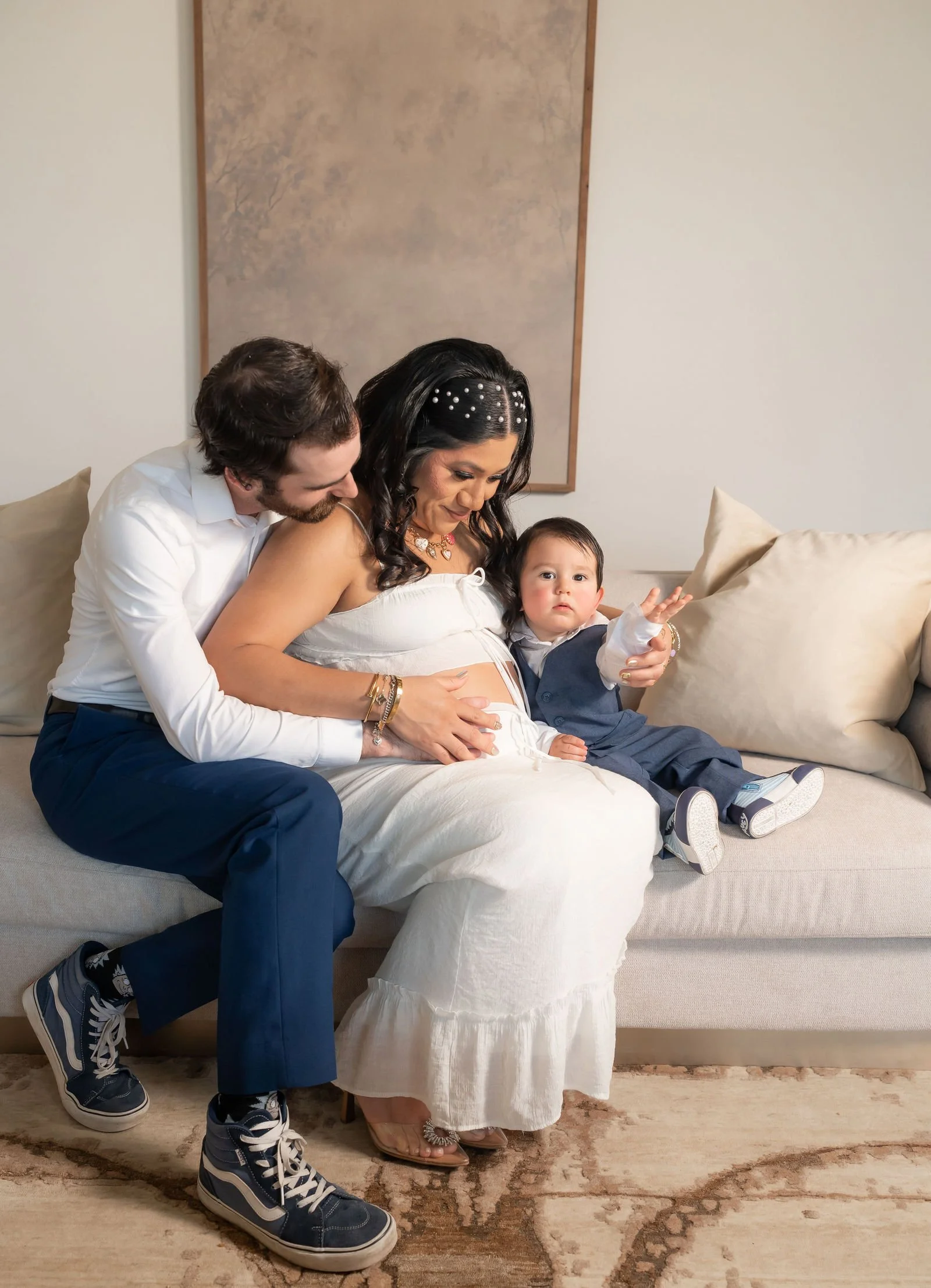 Expectant parents seated with their young child during a family maternity session