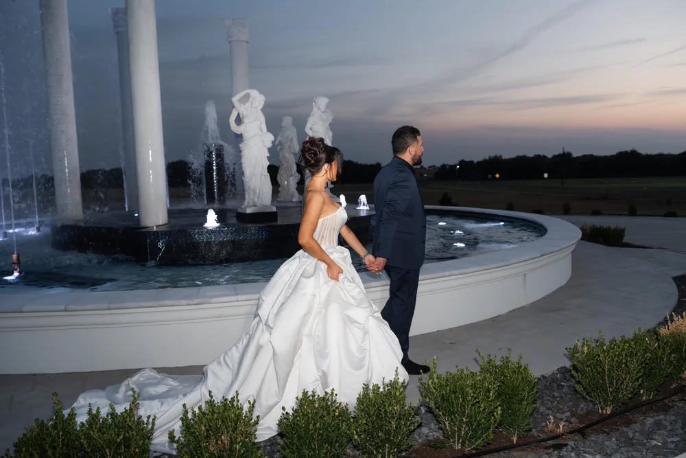 Bride and groom beside an estate fountain in the last light of sunset