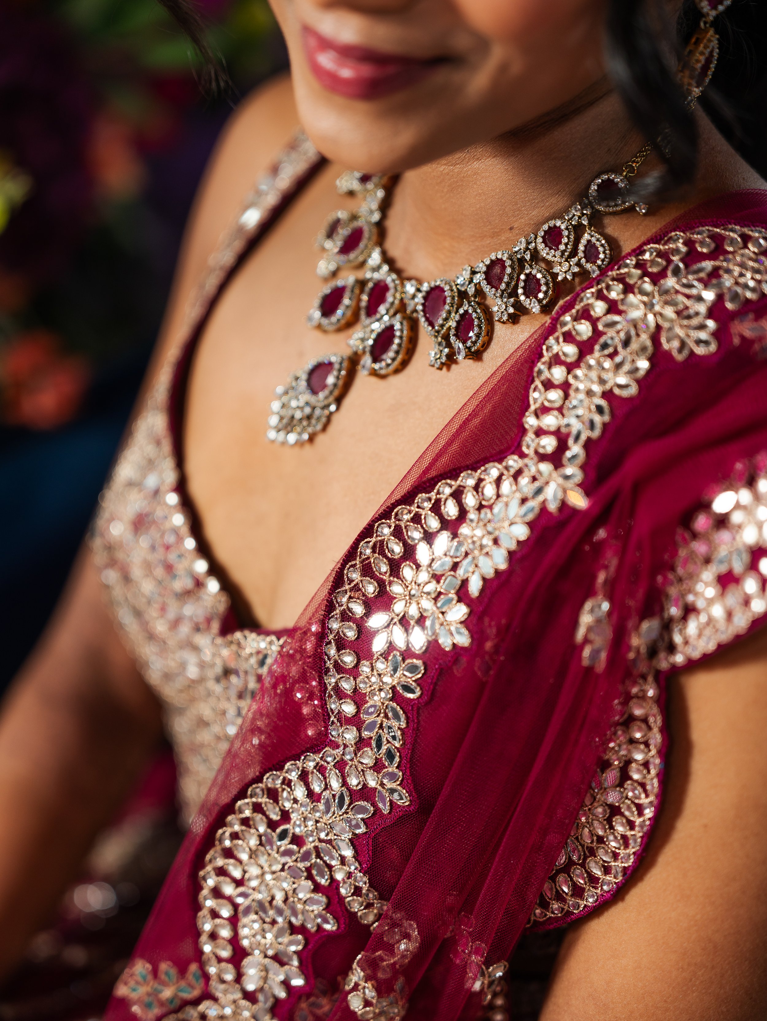 Close-up of a woman in a red and gold sari with ornate jewelry.