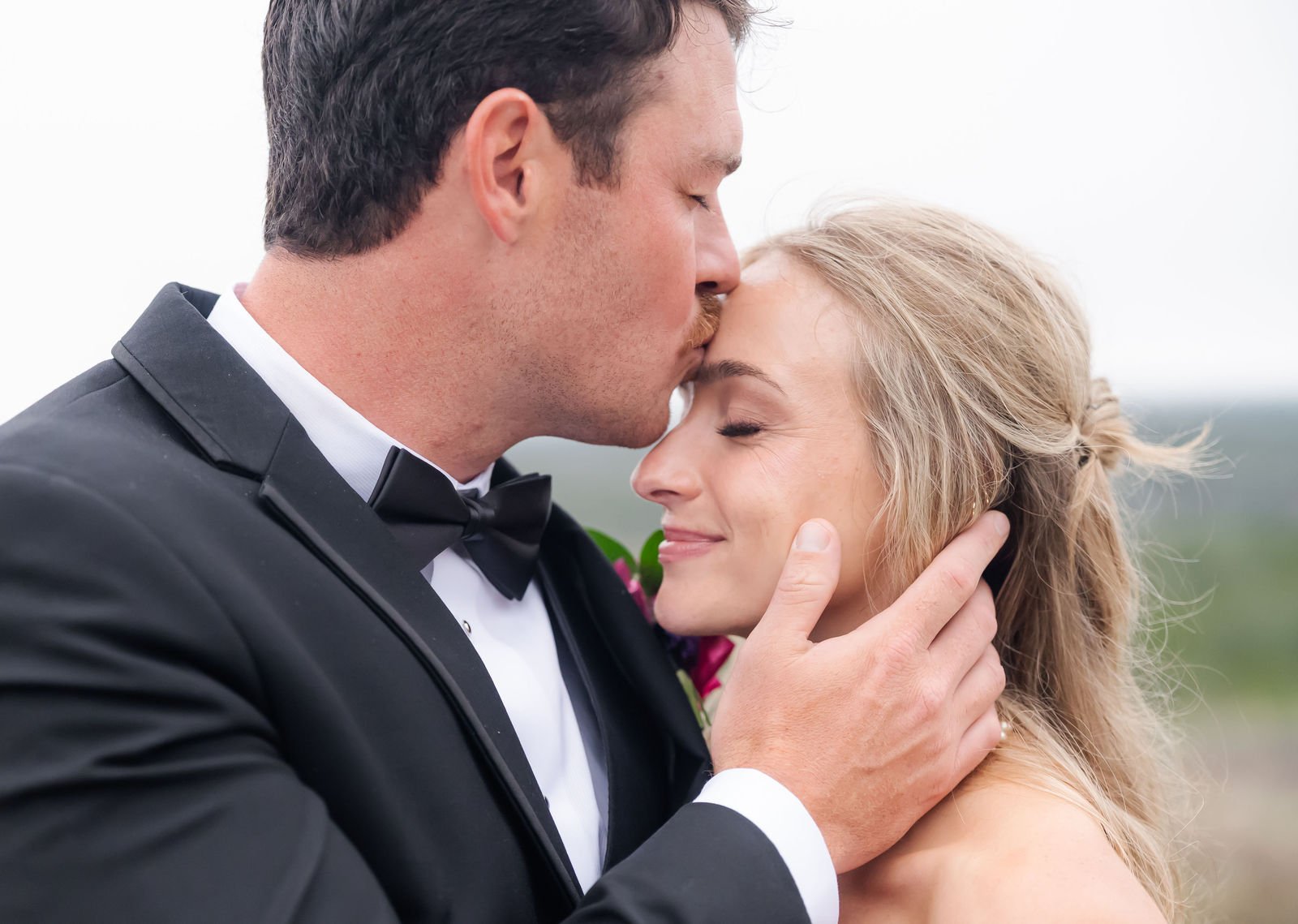 Lily and Steve sharing a quiet wedding portrait as the groom kisses the bride’s forehead