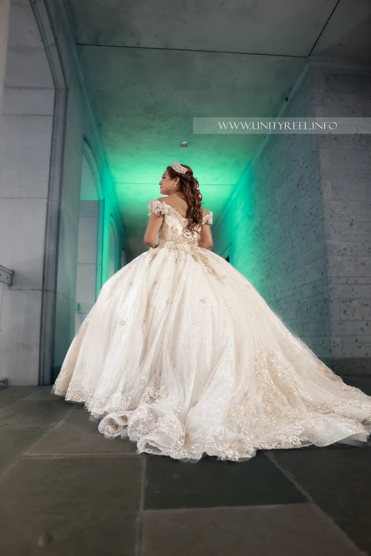 Portrait in an off-shoulder ivory gown with a full skirt in a modern hallway.