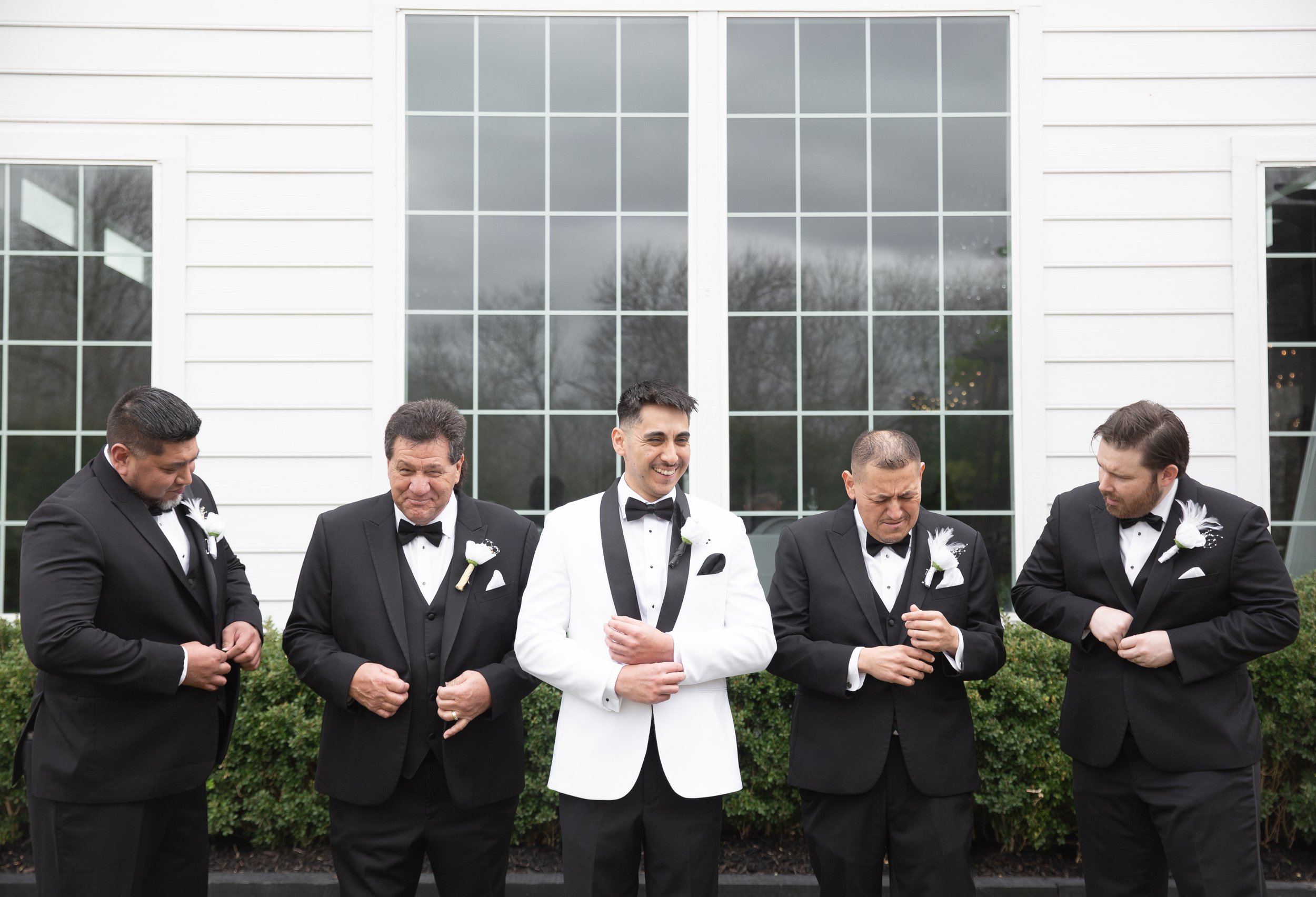 Groom and groomsmen finishing up their look in front of the camera by buttoning jackets and adjusting cufflinks at Venue 311