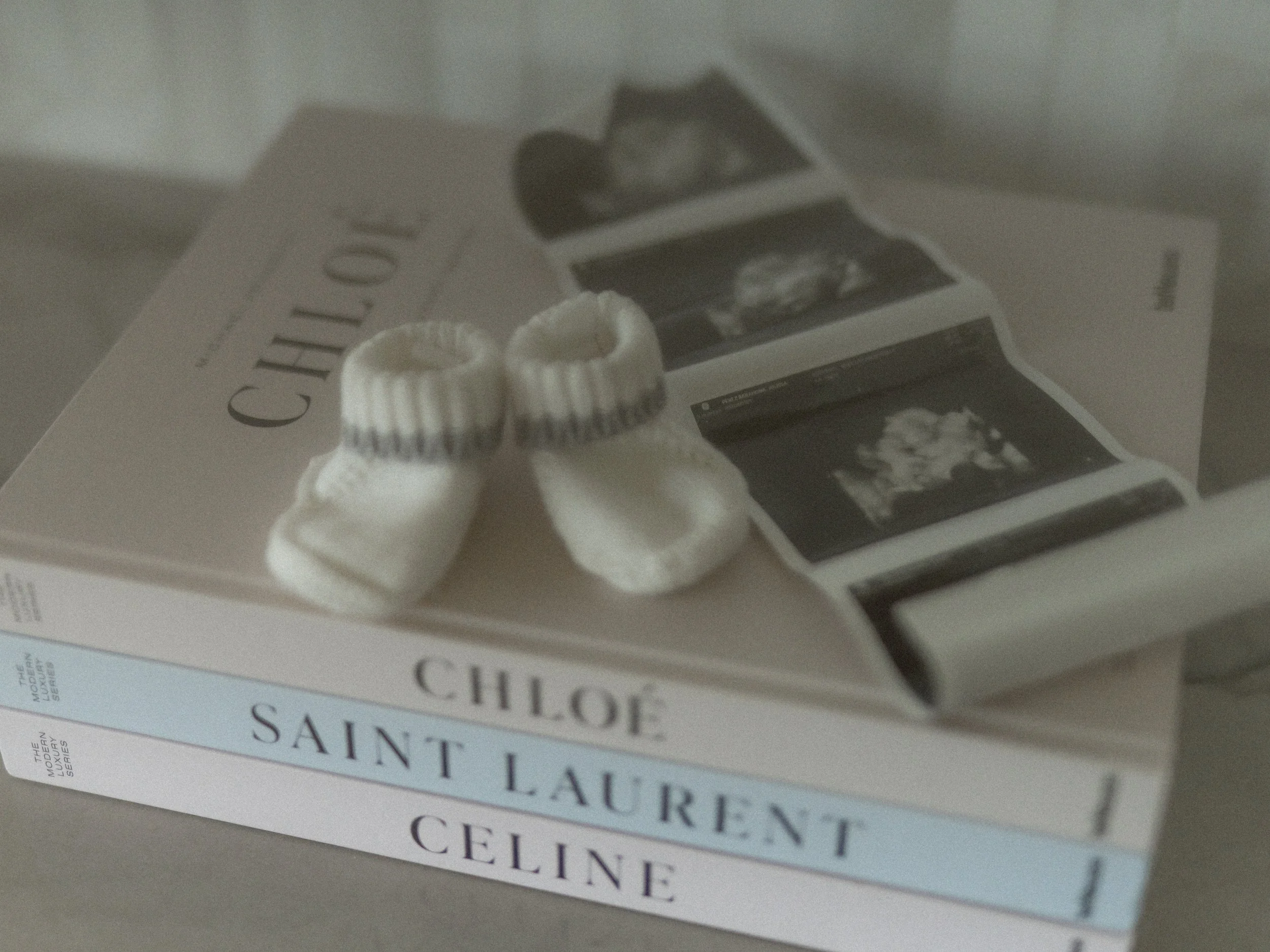 Close-up of a book titled 'Saint Laurent' by Celine. The book is on a gray surface, with a small coil of white string or twine in the foreground and some black-and-white photographs and text visible on the cover.