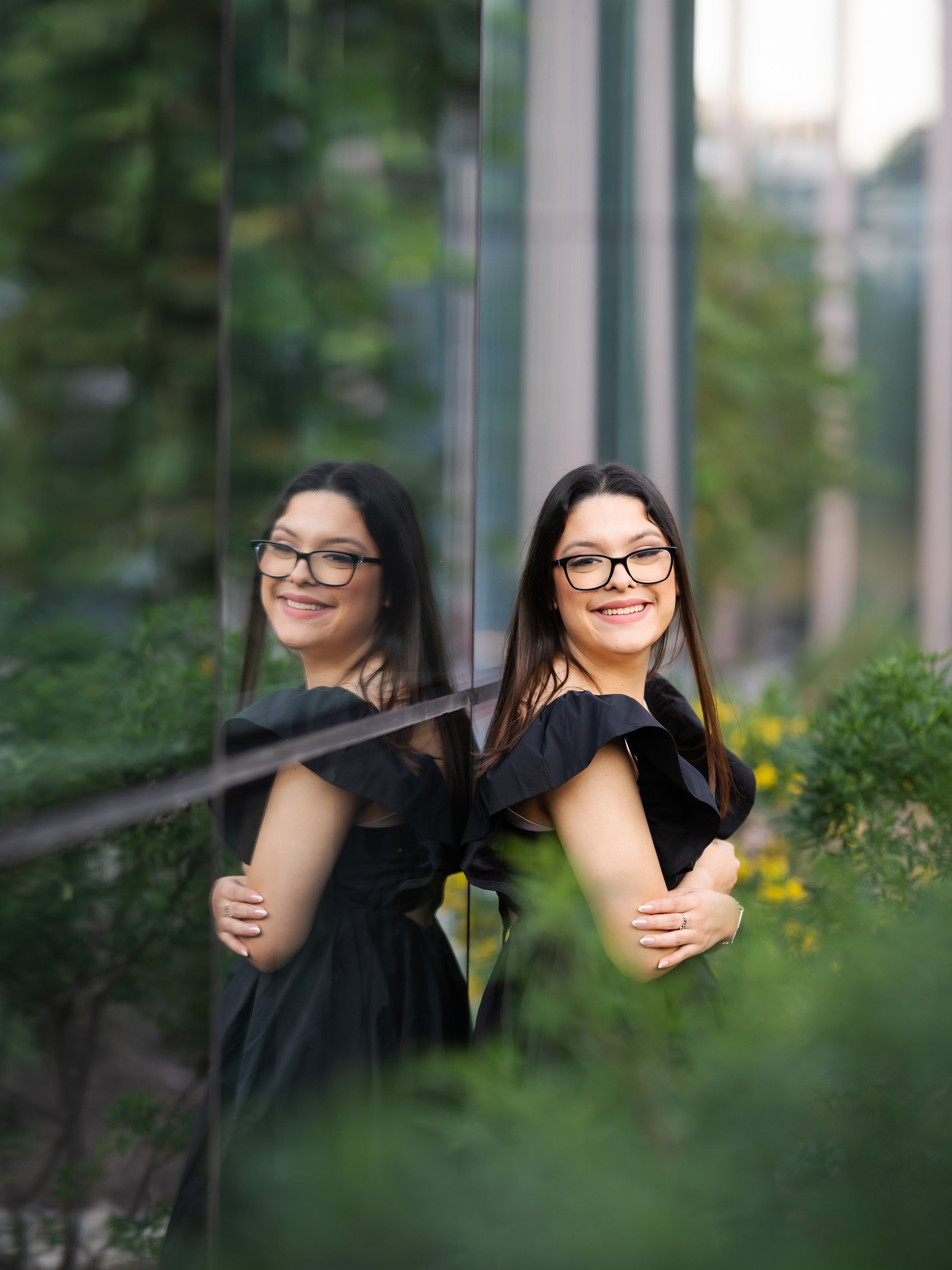 young lady standing with her reflection facing the camera during her graduation photos in Austin
