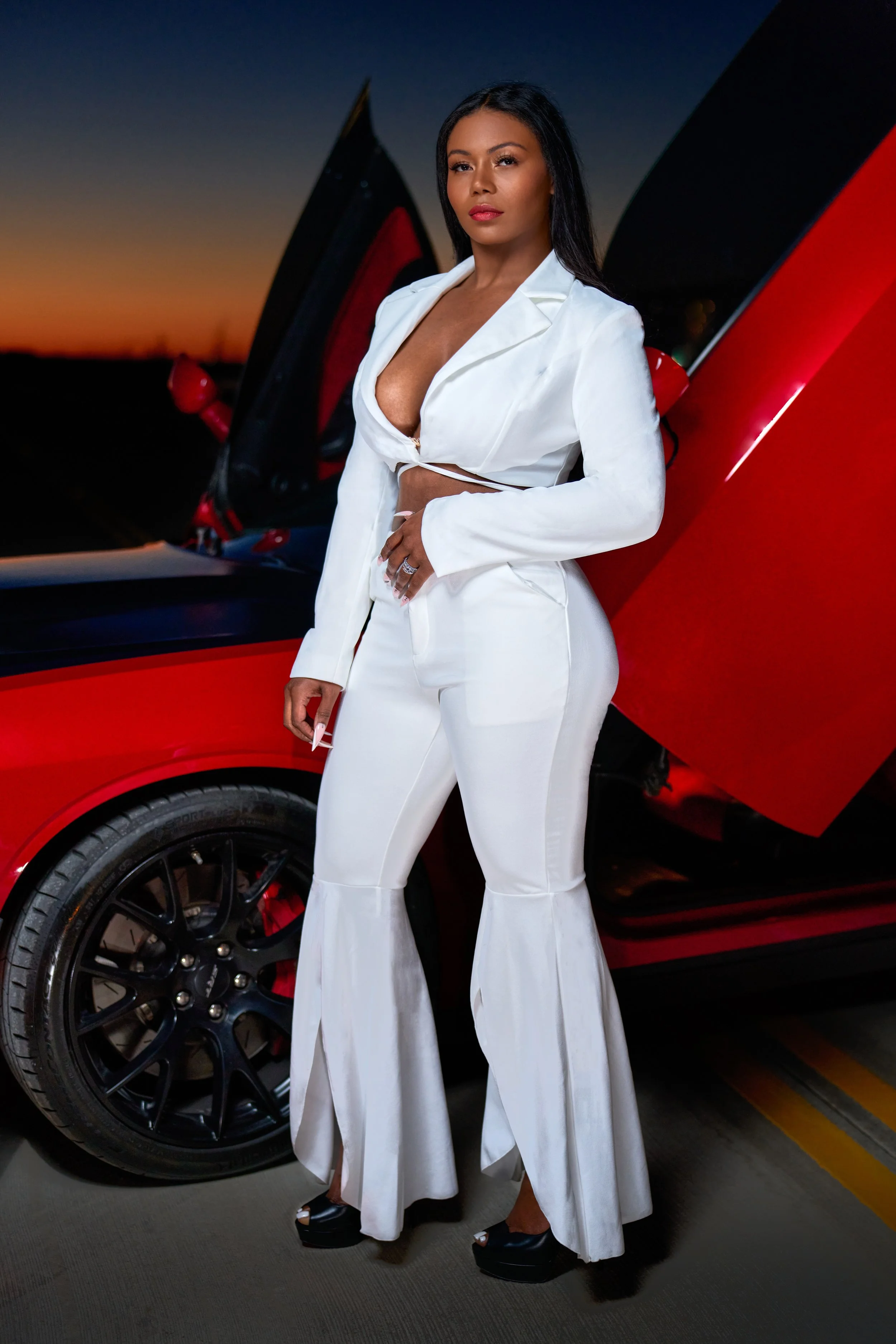 Business owner/Model in white, posing next to Red dodge Hellcat